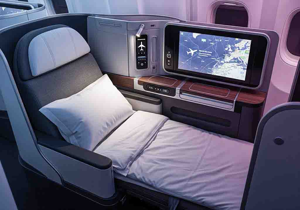 Nahaufnahme eines luxuriösen Business-Class-Sitzes im Flugzeug, der zu einem flachen Bett ausgefahren ist.
